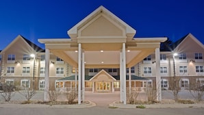 A multi-story hotel with a central entrance, balconies, and a covered walkway.
