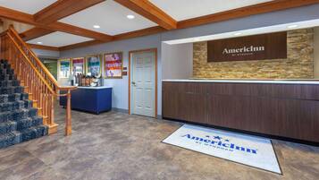 A reception area with a wooden staircase, a reception desk, and a door.