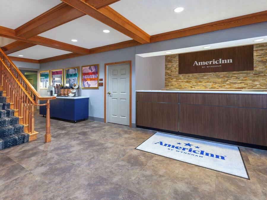 A reception area with a wooden staircase, a reception desk, and a door.