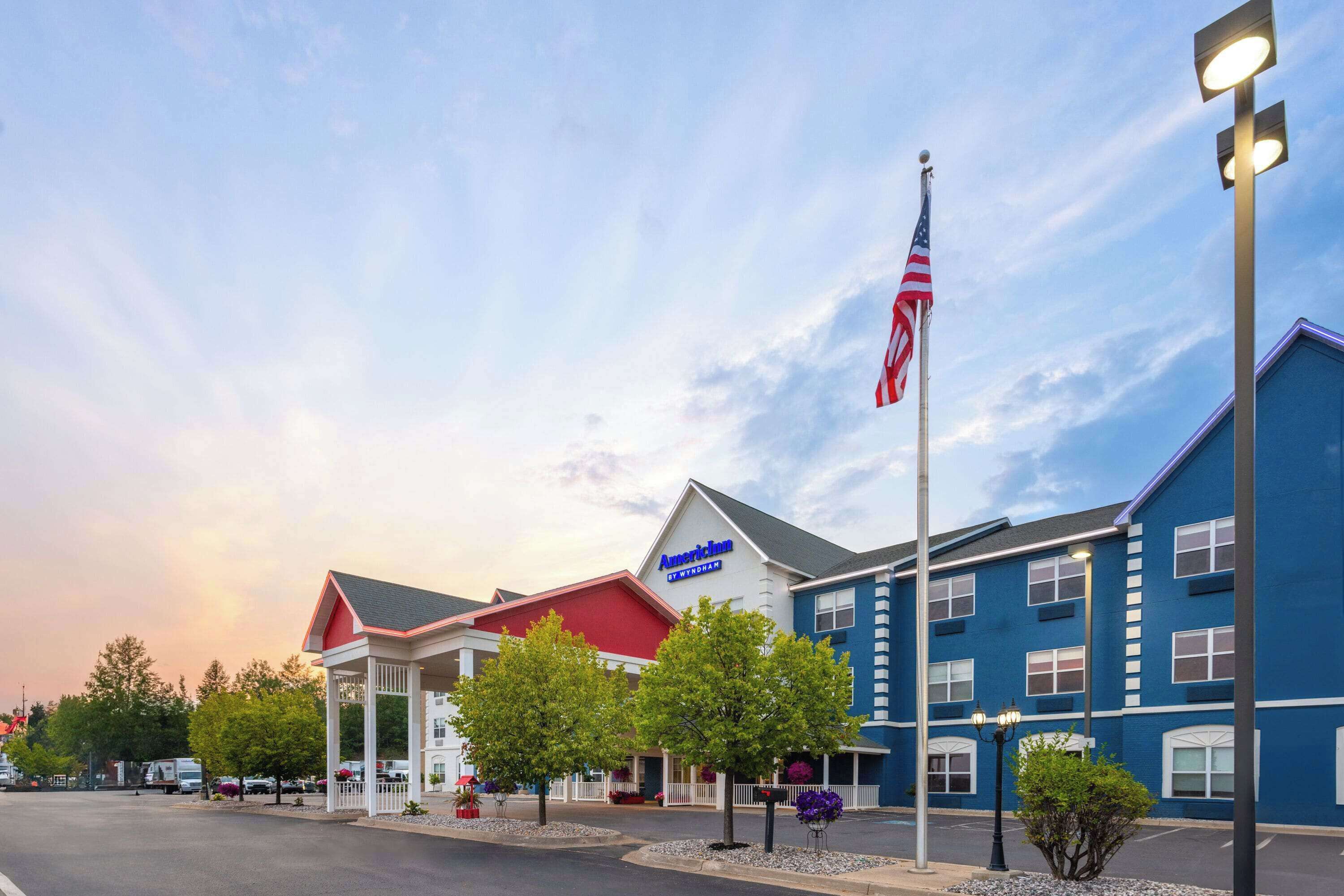 A hotel with a red and white facade, an American flag, and a blue building adjacent to it.