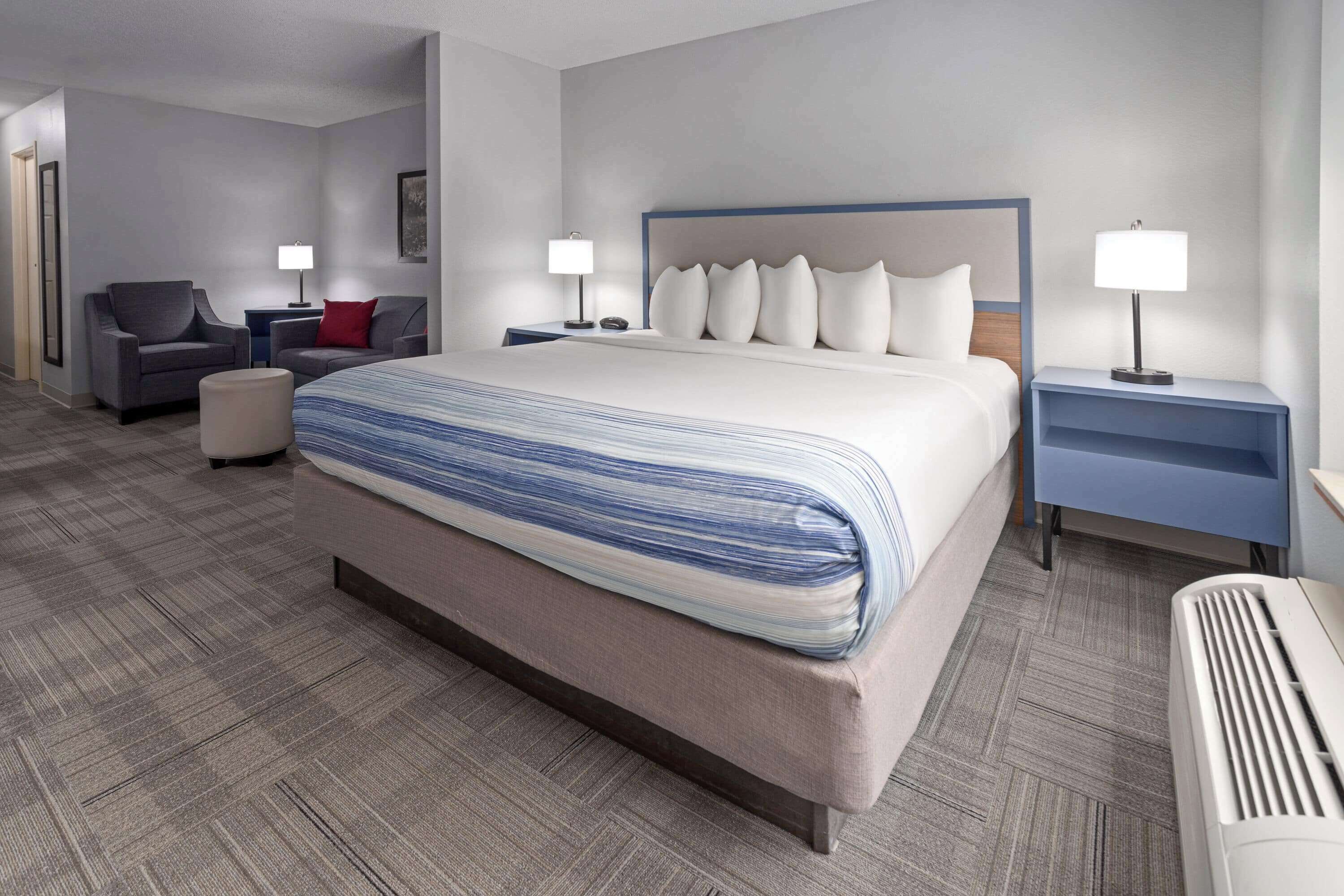 A hotel room with a large bed, two bedside tables, a chair, and a desk.