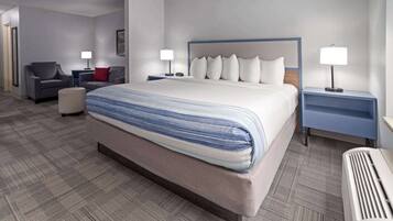 A hotel room with a large bed, two bedside tables, a chair, and a desk.