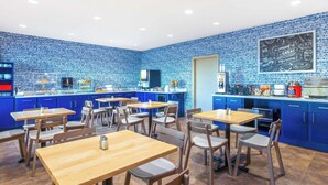 A modern cafe with blue-tiled walls, wooden tables, and blue cabinets.