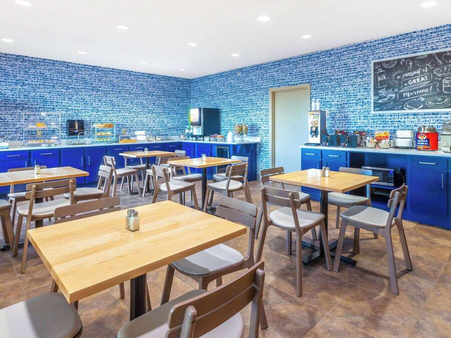 A modern cafe with blue-tiled walls, wooden tables, and blue cabinets.