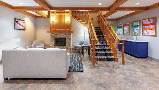 A spacious living area with a large bed, a fireplace, a staircase, and a reception desk.