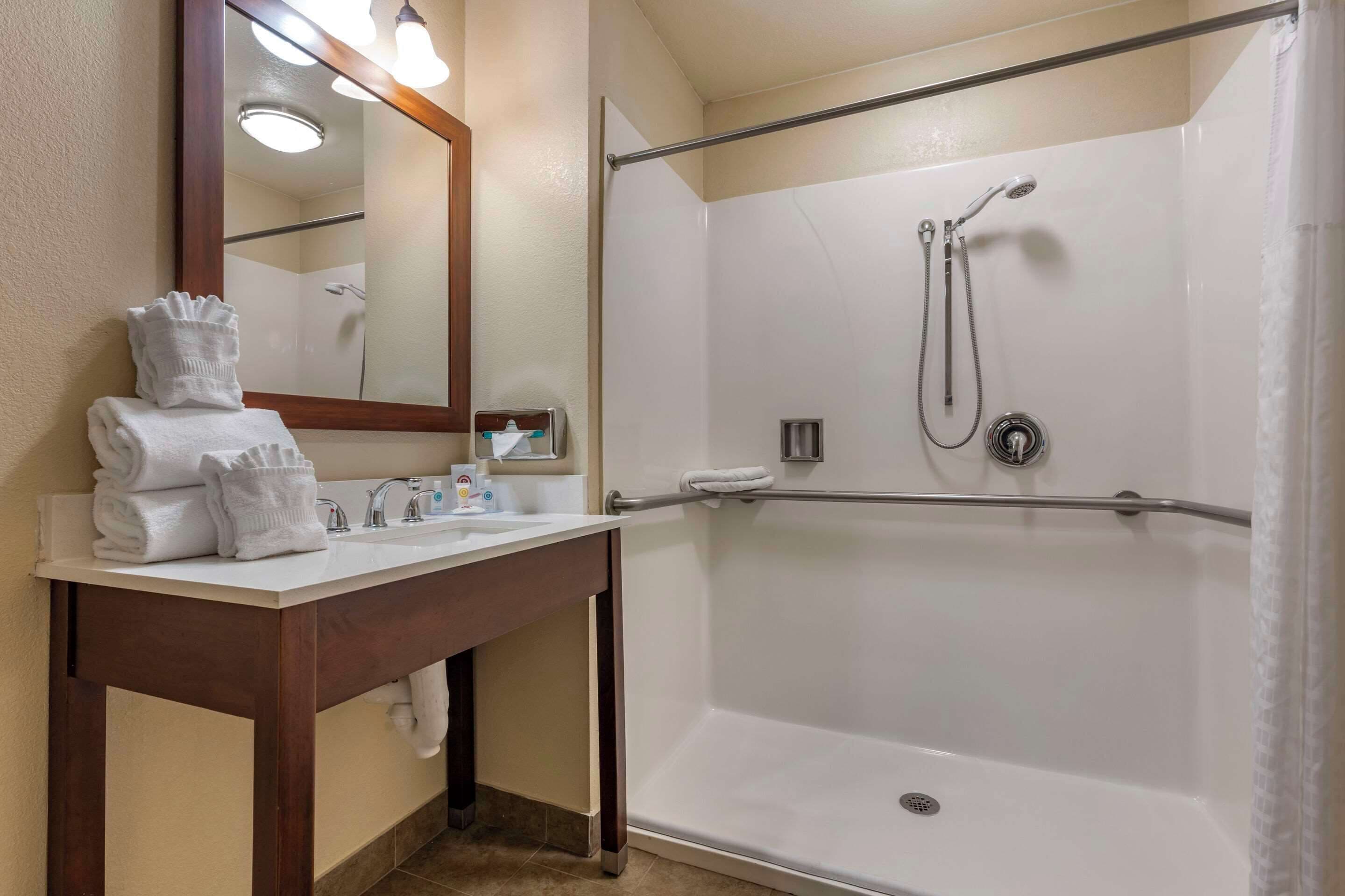 Un baño moderno con lavamanos, espejo y ducha blancos.