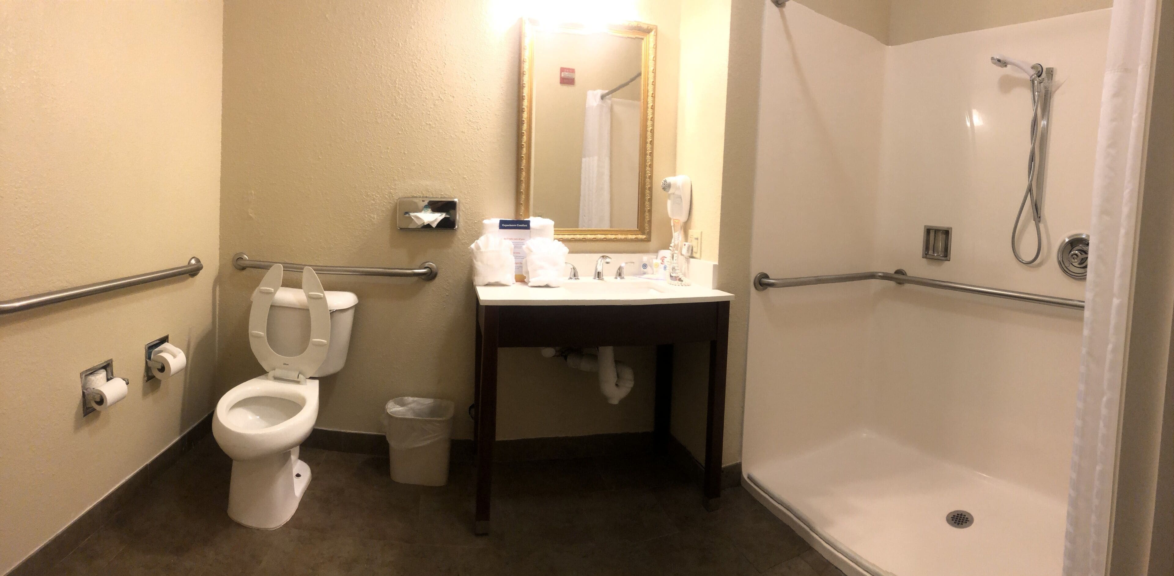Baño con inodoro, lavamanos, espejo y ducha.