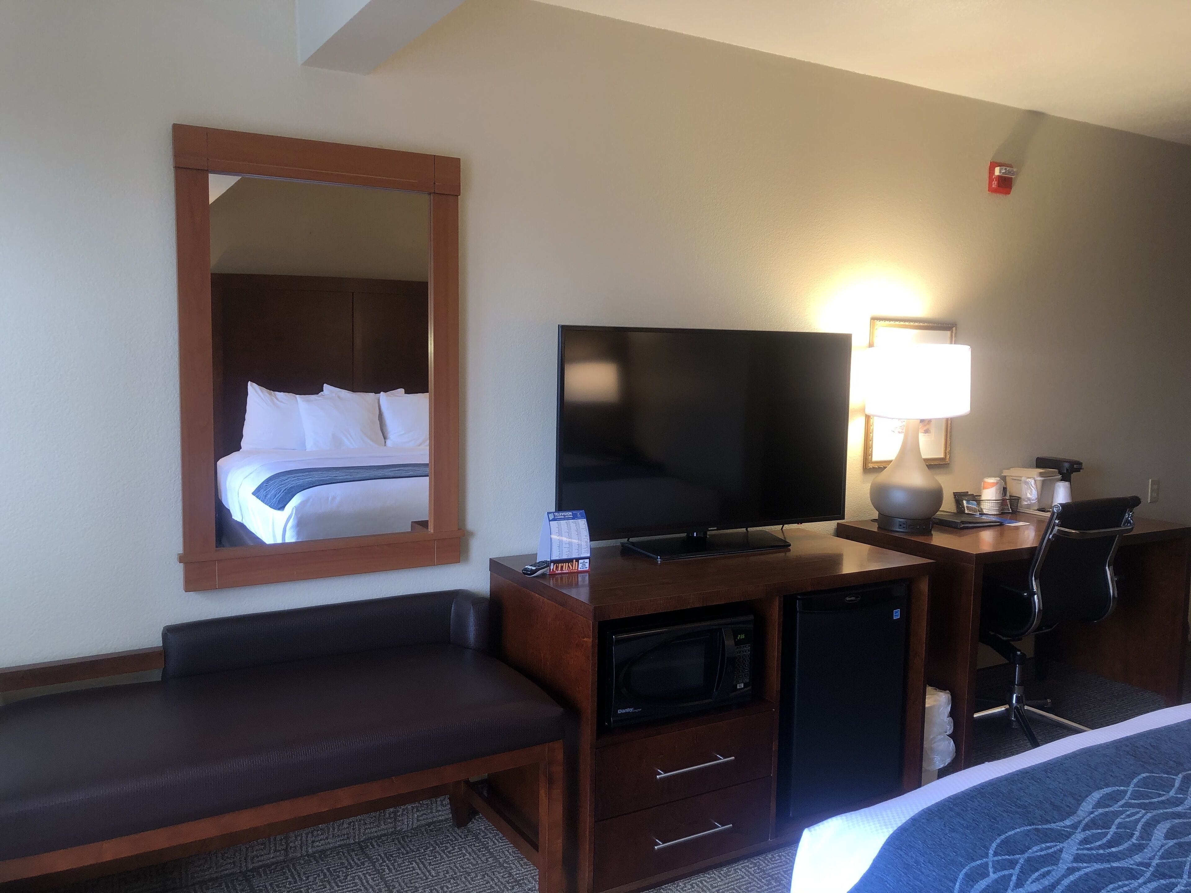 Une chambre d’hôtel équipée d’un lit, d’une télévision, d’un bureau avec une lampe, d’un four à micro-ondes et d’une chaise.