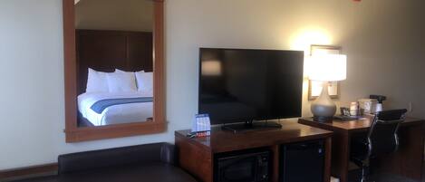 Une chambre d’hôtel équipée d’un lit, d’une télévision, d’un bureau avec une lampe, d’un four à micro-ondes et d’une chaise.