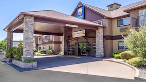 Entrada de hotel con fachada de piedra, un cartel que indica 'Comfort Suites' y un letrero que dice 'Ganador del Premio Oro'.