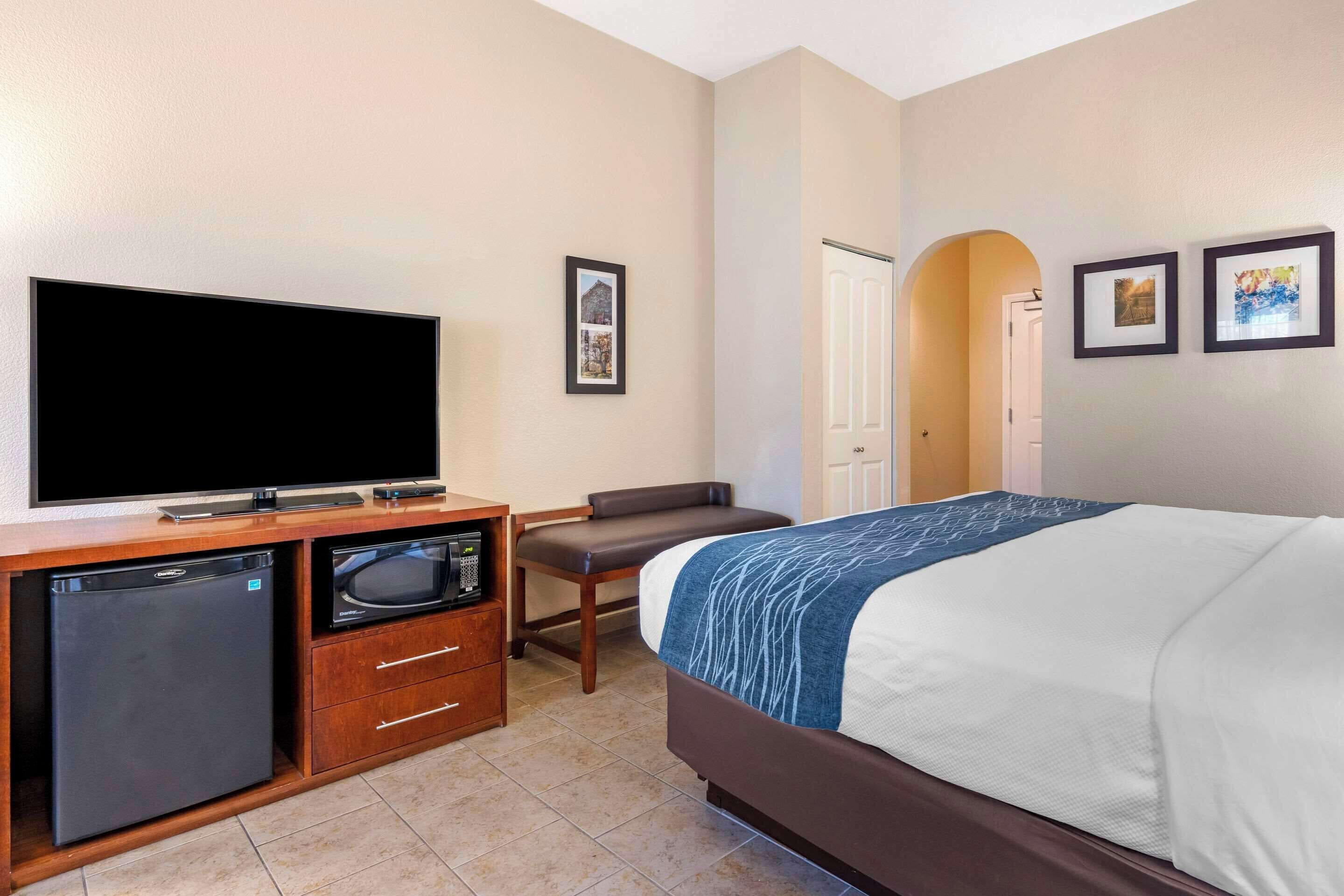 Une chambre d’hôtel équipée d’un lit, d’une télévision, d’un four à micro-ondes, d’un réfrigérateur, d’un bureau et d’une chaise.