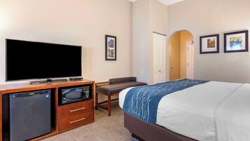Une chambre d’hôtel équipée d’un lit, d’une télévision, d’un four à micro-ondes, d’un réfrigérateur, d’un bureau et d’une chaise.