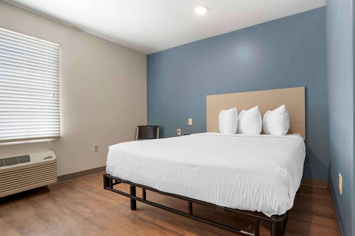 A bedroom with a bed, a heater, a window with blinds, and a blue wall.