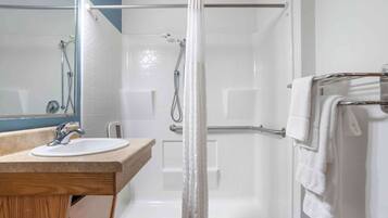 A modern bathroom with a glass-enclosed shower, a wooden vanity with a sink, and a towel rack.