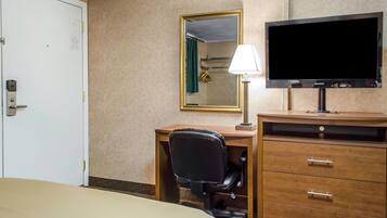 Une chambre d’hôtel comprenant un lit, un bureau avec une chaise, une télévision, un miroir et une commode.