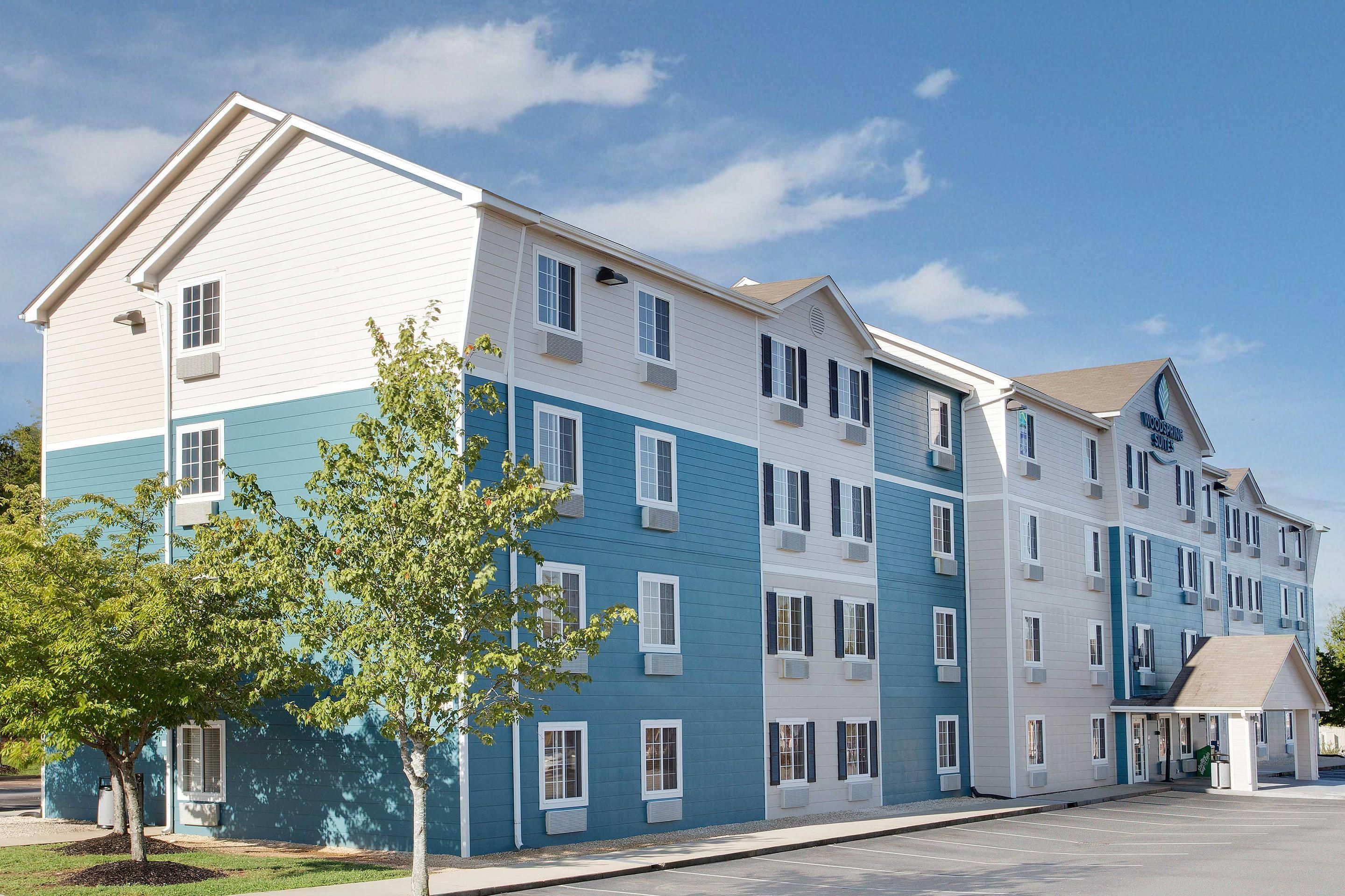 A multi-story hotel with a modern design, featuring a mix of blue and white exterior colors, large windows, and a covered entrance area.