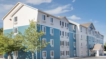 A multi-story hotel with a modern design, featuring a mix of blue and white exterior colors, large windows, and a covered entrance area.