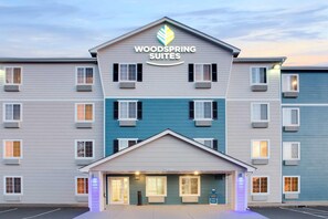 A multi-story hotel with a prominent 'WOODSPRING SUITES' sign. - WoodSpring Suites Charlotte Shelby (Shelby)
