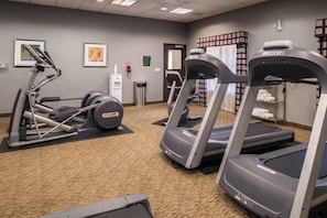 A fitness center with treadmills, a weight machine, and a water dispenser.