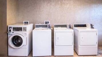 Four white front-loading washing machines in a row against a plain wall.
