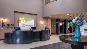A hotel reception area with a reception desk, a wall-mounted sign, and a vase with flowers. - Holiday Inn Ontario Airport by IHG (Ontario)