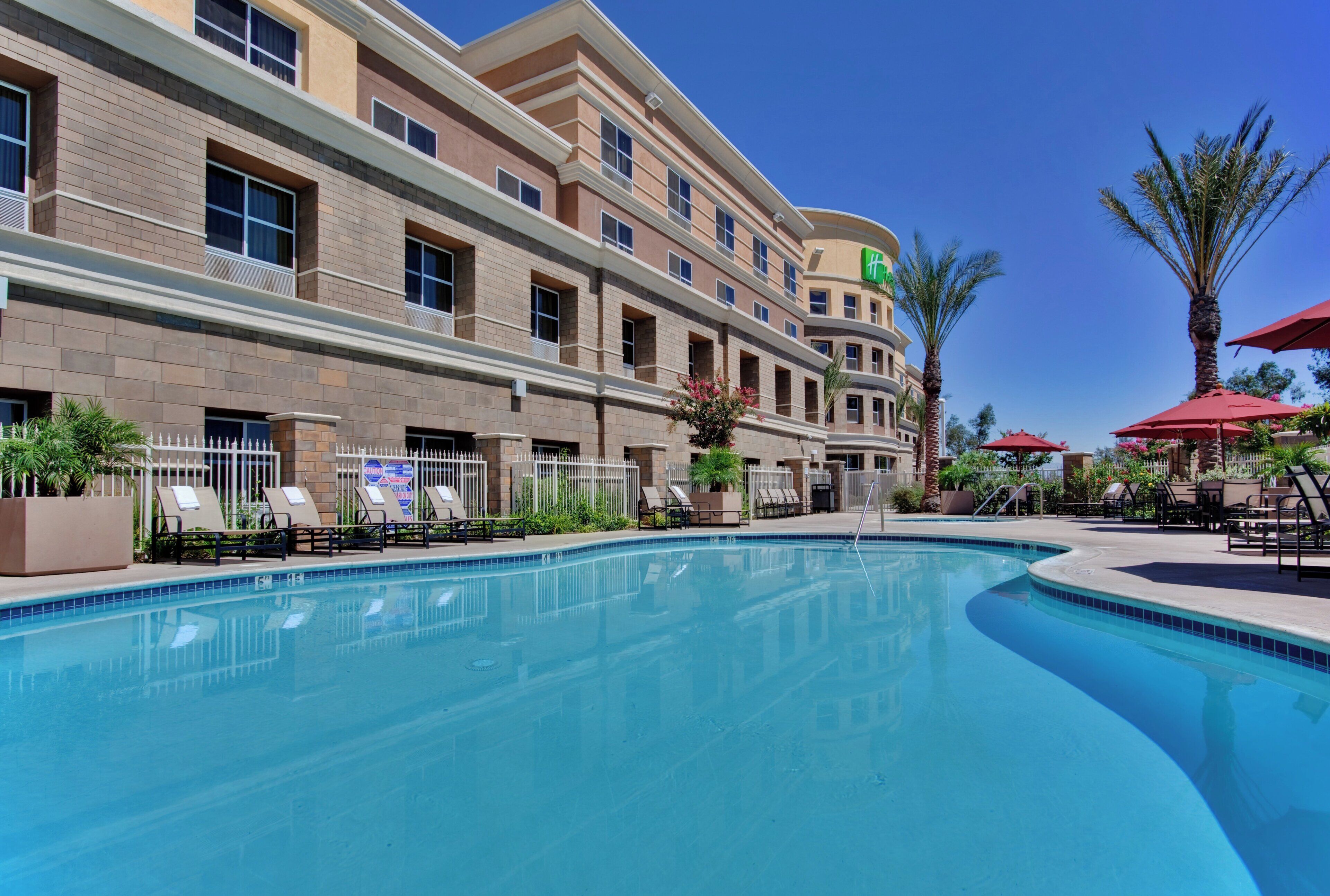 A hotel with a swimming pool, multiple floors, and outdoor seating areas.