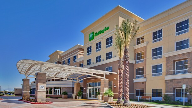 A Holiday Inn hotel with a covered entrance, palm trees, and a clear blue sky. - Holiday Inn Ontario Airport by IHG (Ontario)