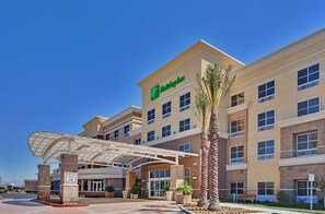 A Holiday Inn hotel with a covered entrance, palm trees, and a clear blue sky. - Holiday Inn Ontario Airport by IHG (Ontario)