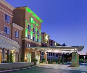 A Holiday Inn hotel with a covered entrance, multiple floors, and a well-lit facade.