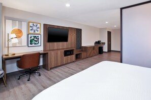 A modern hotel room with a wooden desk, a flat-screen TV, a bed, and artwork on the wall. - Holiday Inn Ontario Airport by IHG (Ontario)