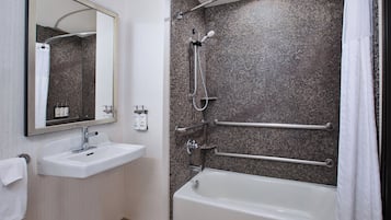 A modern bathroom with a white sink, mirror, and bathtub.