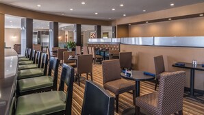 A hotel lobby with a long counter, seating area with patterned chairs, and a striped carpet.