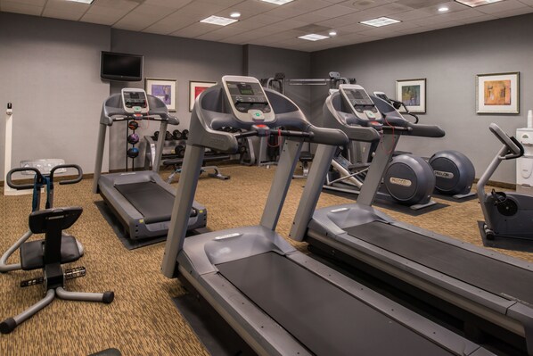 A gym with treadmills, elliptical machines, and a television mounted on the wall. - Holiday Inn Ontario Airport by IHG (Ontario)