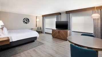 Una habitación de hotel con cama, televisor, escritorio, silla y mesa de comedor.