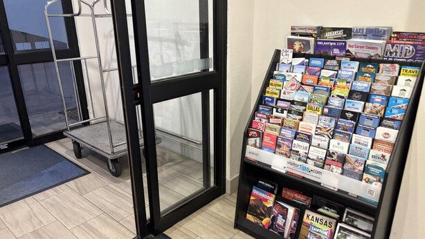 A reception area with a glass door, a metal cart, and a display of travel brochures.