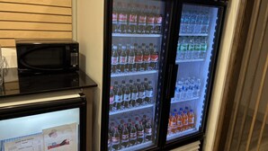 A beverage refrigerator stocked with various drinks, a microwave, and a digital display.