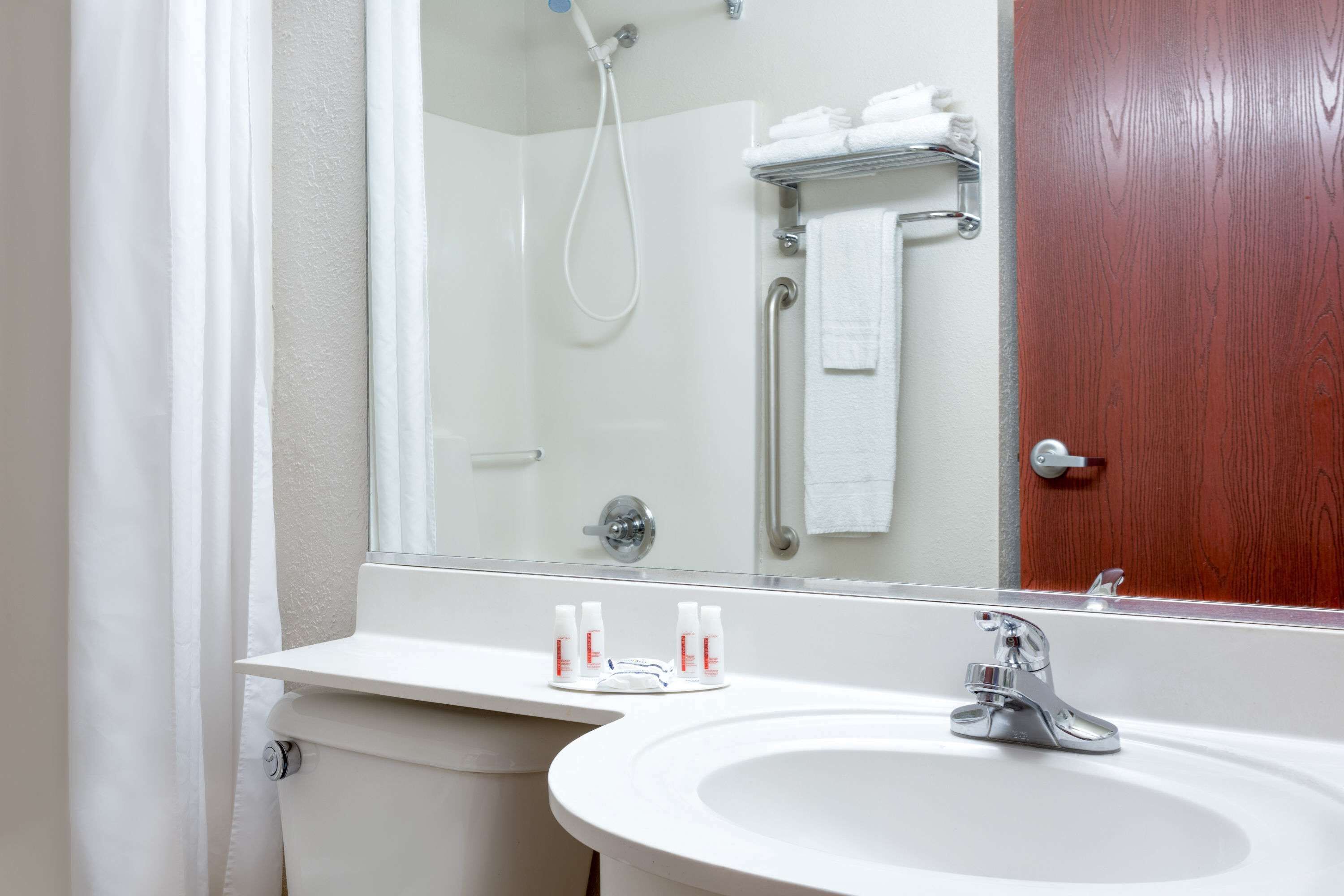 A bathroom with a white sink, a mirror, and a shower.