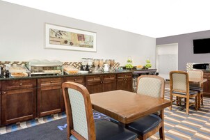 Una cocina de hotel con mesas de buffet, armarios de madera y un televisor montado en la pared.