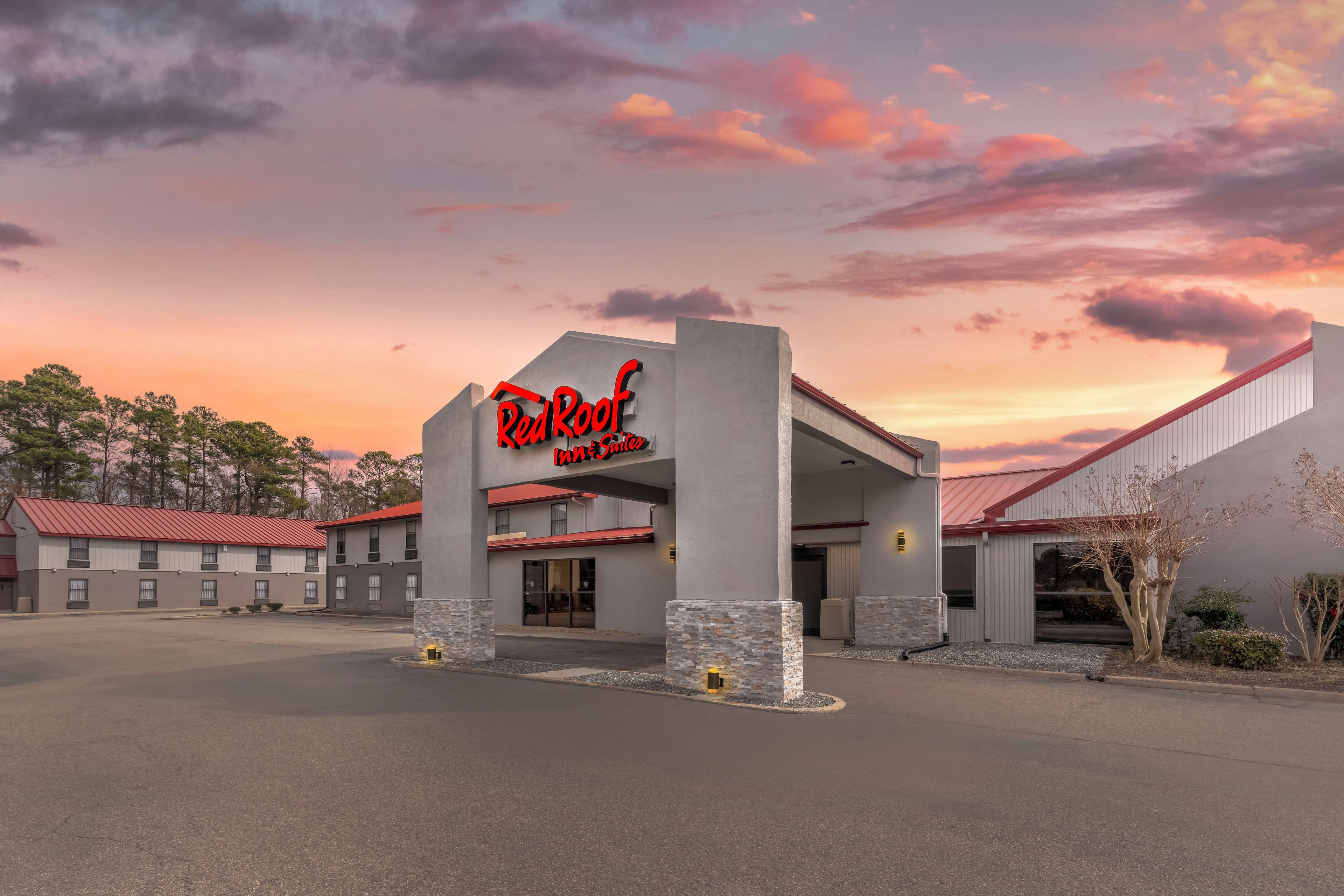 A Red Roof Inn & Suites with a modern architectural design, featuring a prominent entrance and a parking area.