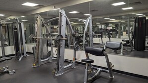 Une salle de sport équipée de divers appareils d’exercice, de miroirs et dotée d’un sol noir.