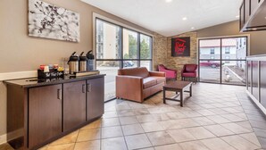 Un intérieur moderne comprenant un espace cuisine, un coin salon avec un canapé et des fauteuils, et une grande fenêtre offrant une vue sur l’extérieur.