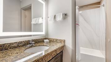 Een bad/douchecombinatie, handdoeken, zeep, shampoo