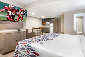 Ein Hotelzimmer mit Bett, Schreibtisch, Fernseher, Küchenzeile und Bad.