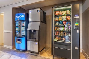 Ein Getränkeautomat mit Pepsi-Logo, ein Wasserspender und ein Snackautomat mit verschiedenen Marken.