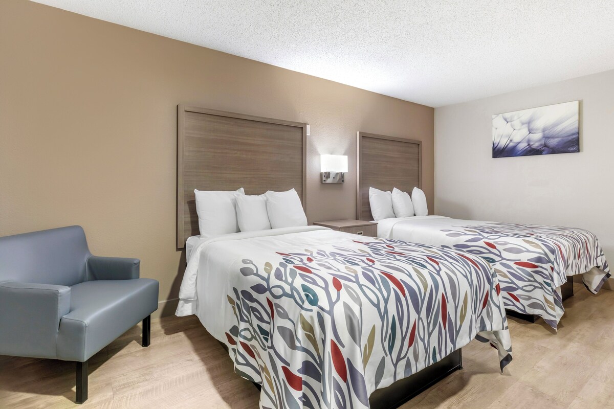 Ein Hotelzimmer mit zwei Betten, einer Couch und einer Wandleuchte.