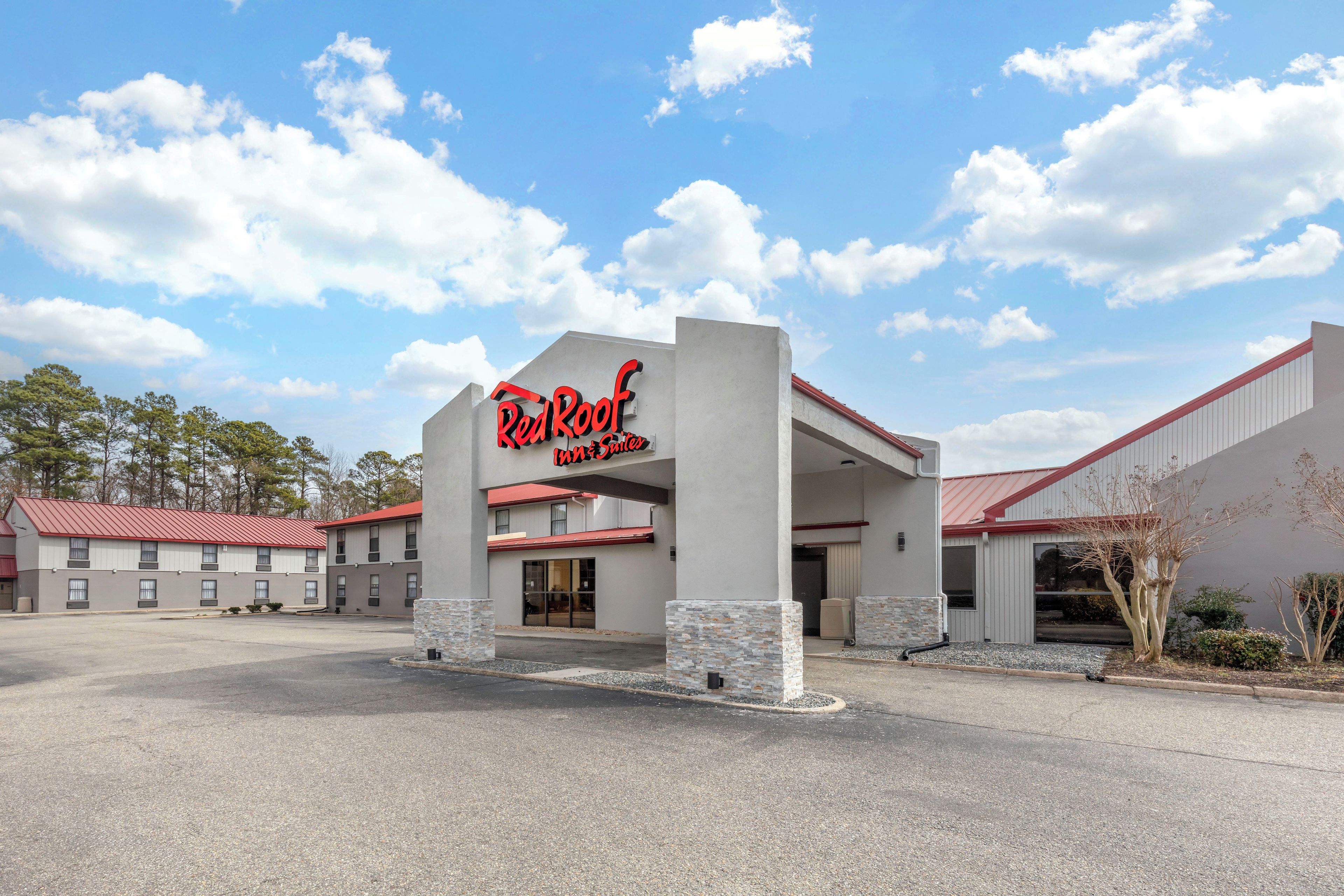 A Red Roof Inn with a modern architectural design, featuring a prominent entrance and a parking lot.