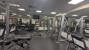 Une salle de sport équipée de divers appareils d’exercice, notamment des tapis de course, des appareils de musculation et des poids libres.