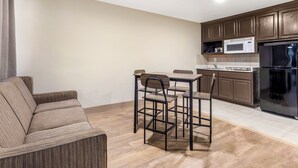 Un espace de vie compact comprenant un coin cuisine, un coin repas avec une table et des chaises, et un canapé.