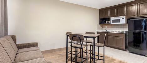 A compact living space with a kitchenette, a dining area with a table and chairs, and a sofa.