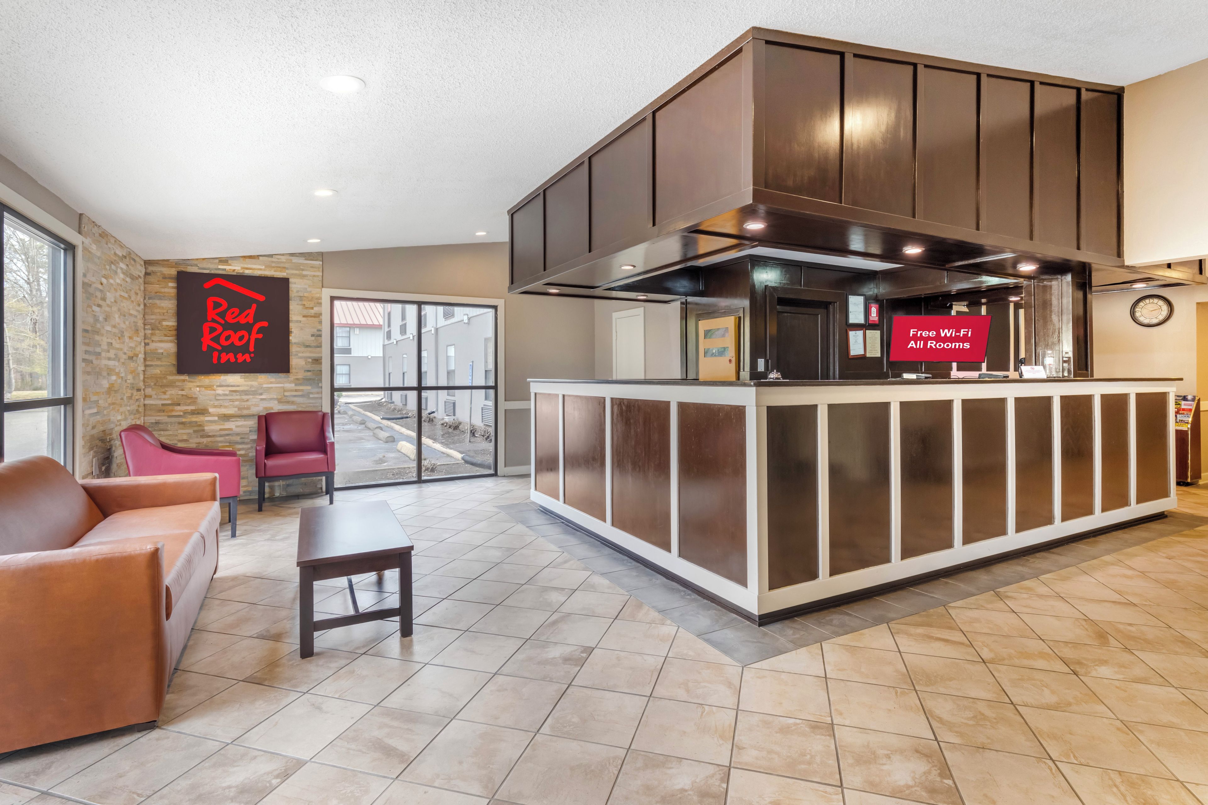 A Red Roof Inn lobby with a reception desk, seating area, and a view of the outside.
